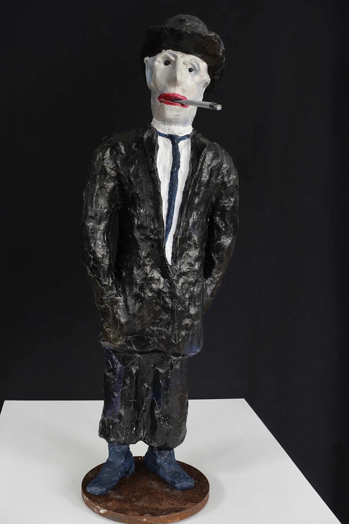 "Raucher mit Bowler-Hut", figurative Skulptur, angelehnt an die Darstellungen von René Magritte, im Vergleich zu den eleganten Vorbildern etwas heruntergekommen, aus Drahtgeflecht, Gipsbinden, Hut und Anzug mit schwarzer Acrylfarbe , rote Lippen, Zigarette im Mundwinkel